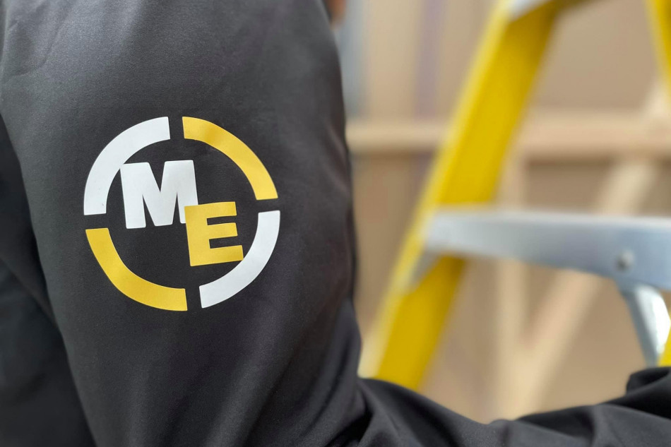 A person wearing a black jacket with the Mech-Elec logo on it.